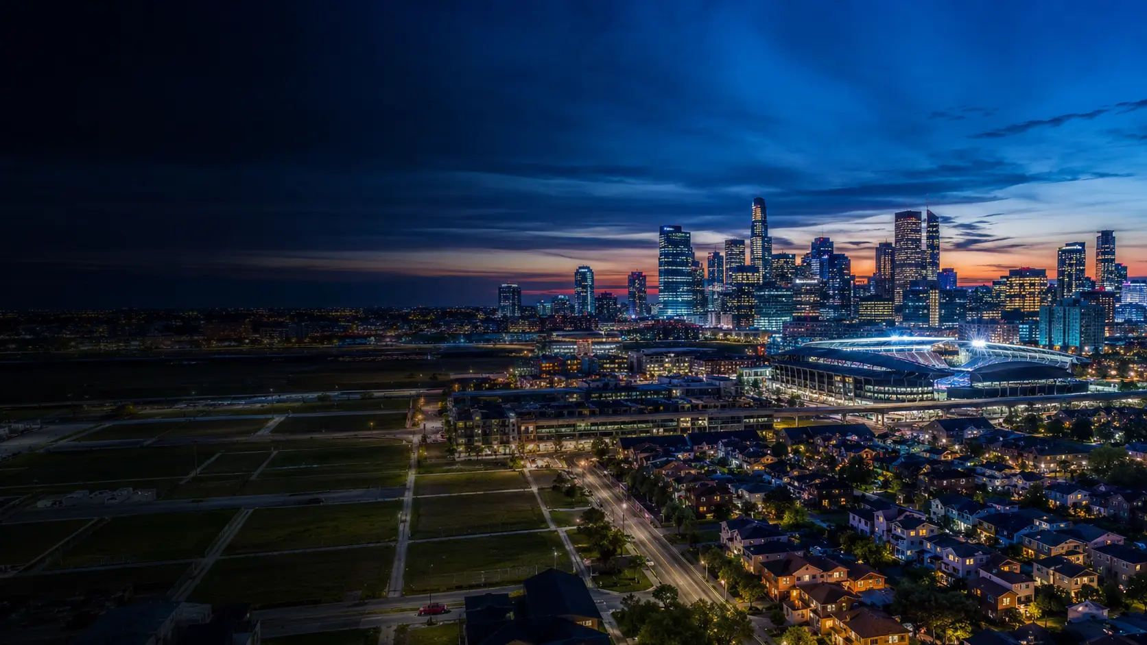 American city, residential neighborhoods, and a stadium at blue hour